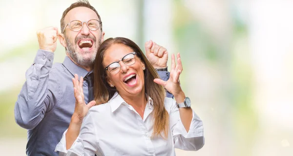 中年拉美裔夫妇在爱戴眼镜在孤立的背景庆祝疯狂和疯狂的成功与胳膊举起和闭着眼睛尖叫兴奋 获奖者概念 — 图库照片