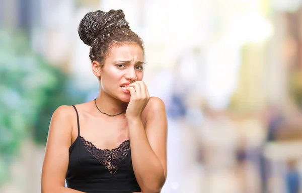 Young braided hair african american with pigmentation blemish birth mark over isolated background looking stressed and nervous with hands on mouth biting nails. Anxiety problem.