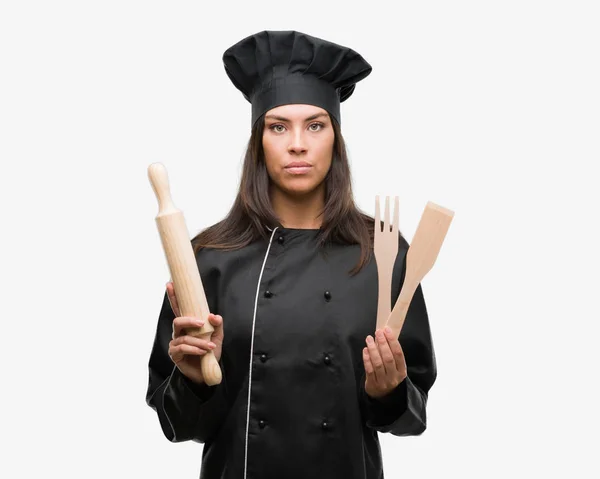 年轻的西班牙裔厨师妇女穿着厨师制服与自信的表情 聪明的脸认真思考 — 图库照片
