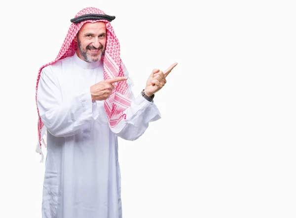 笑顔で側に つの手と指で指しているカメラを見て孤立の背景にクーフィーヤ身に着けているアラブの年配の男性 — ストック写真