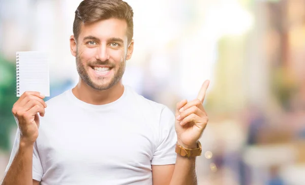 Joven Hombre Guapo Sosteniendo Cuaderno Sobre Fondo Aislado Muy Feliz — Foto de Stock