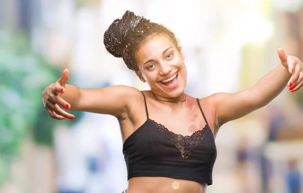 Young braided hair african american with pigmentation blemish birth mark over isolated background looking at the camera smiling with open arms for hug. Cheerful expression embracing happiness.