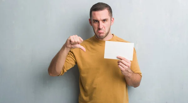 Kaukasische Jongeman Grijs Grunge Muur Met Blanco Kaart Met Boos — Stockfoto