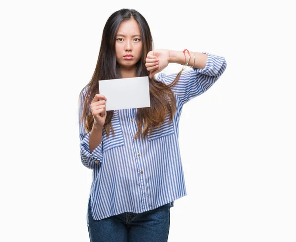 年轻的亚洲妇女持有空白卡在孤立的背景与愤怒的脸 — 图库照片