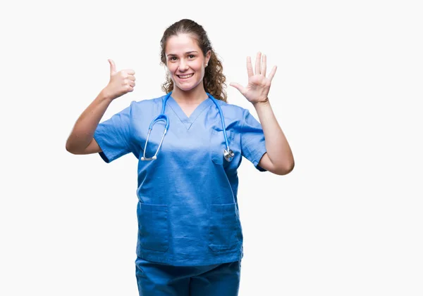 年轻的黑发医生女孩穿着护士或外科医生制服在孤立的背景显示和指向与手指数字六 同时微笑着自信和快乐 — 图库照片
