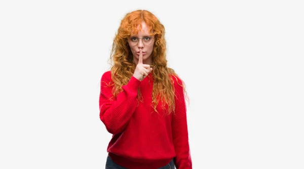 唇に指で静かにするように求めている赤いセーターを着ている若い赤毛の女性 沈黙と秘密の概念 — ストック写真