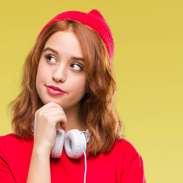 Genç güzel hipster kadın çene düşünme hakkında soru, dalgın ifade üzerinde kulaklık ve el ile kap giyen arka plan izole. Düşünceli yüzüyle gülümsüyor. Şüphe kavramı.