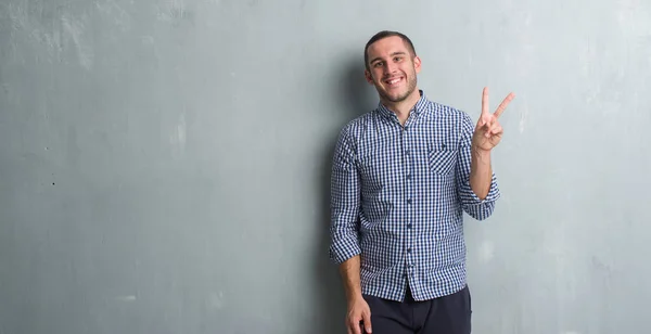 Young Caucasian Man Grey Grunge Wall Smiling Happy Face Winking — Stock Photo, Image