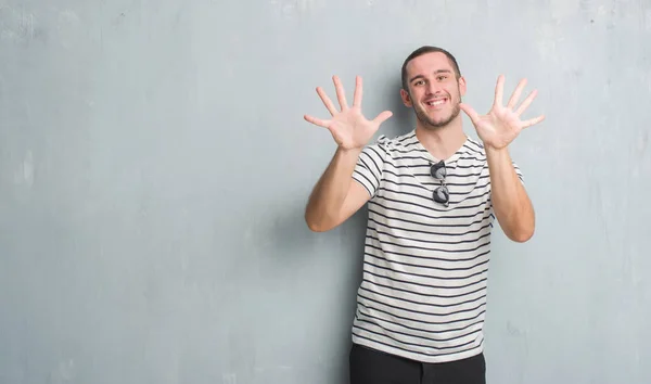 Joven Caucásico Hombre Sobre Gris Grunge Pared Mostrando Apuntando Hacia —  Fotos de Stock