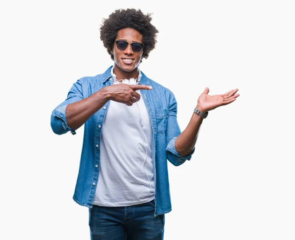 美国黑人戴着耳机听音乐在孤立的背景下 用手和手指指着 对着镜头微笑 — 图库照片