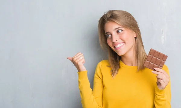 Schöne Junge Frau Über Grunge Grauer Wand Die Schokoriegel Zeigt — Stockfoto