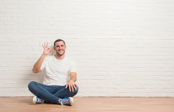 Young Caucasian Man Sitting Floor White Brick Wall Smiling Positive — Stock Photo, Image