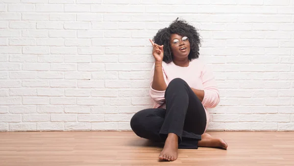 Mujer Afroamericana Joven Sentada Suelo Casa Señalando Con Dedo Hacia — Foto de Stock