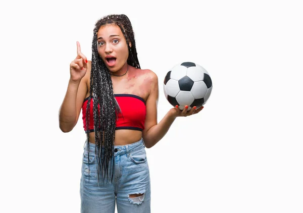 年轻的编织头发非洲裔美国人与出生标记举行足球在孤立的背景惊讶的想法或问题用快乐的脸指指点点 — 图库照片
