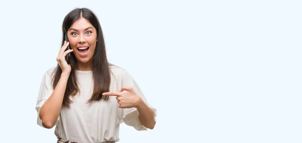 Junge Schöne Hispanische Mit Smartphone Mit Überraschung Gesicht Zeigt Mit — Stockfoto