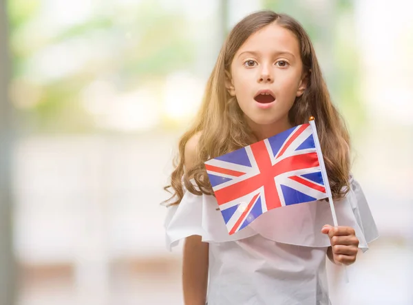 驚き顔 恐怖表現と興奮とショックで怖いイギリスの旗を保持しているヒスパニックのブルネットの少女 — ストック写真