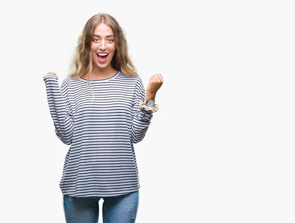 孤立した背景を祝う上のストライプのセーターを着て美しい若いブロンドの女性驚いて腕を上げると成功のため驚くし 目を開きます 勝者の概念 — ストック写真