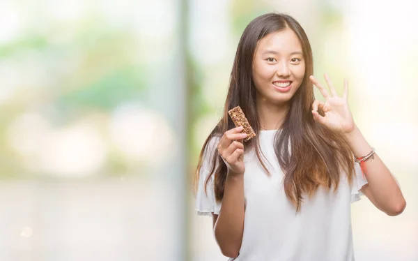 Young Asian Woman Eating Chocolate Energetic Bar Isolated Background — Stock Photo, Image