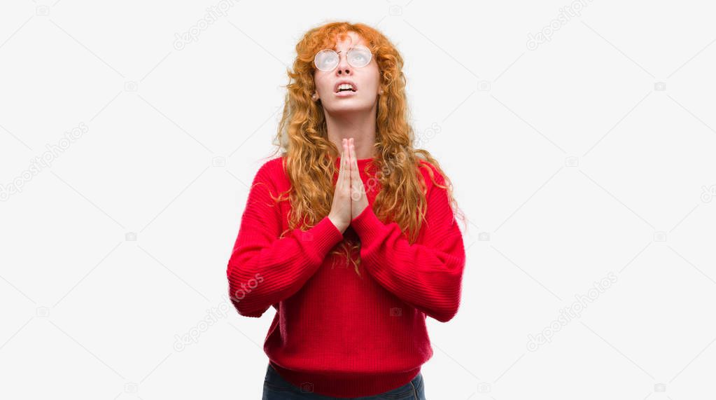 Young redhead woman wearing red sweater begging and praying with hands together with hope expression on face very emotional and worried. Asking for forgiveness. Religion concept.