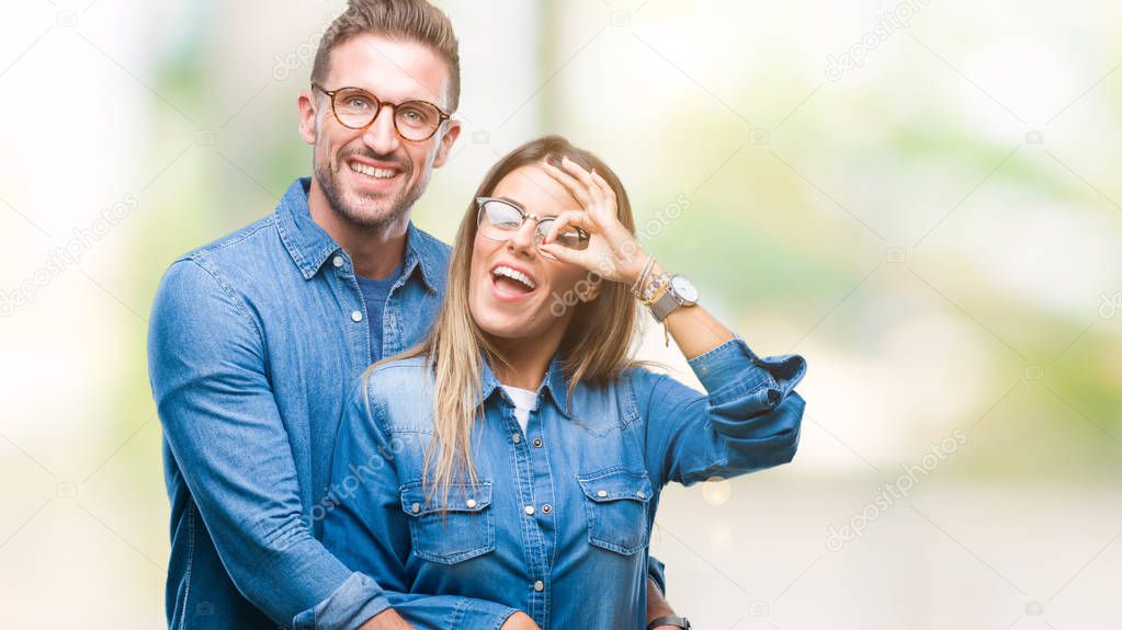 Young couple in love wearing glasses over isolated background doing ok gesture with hand smiling, eye looking through fingers with happy face.