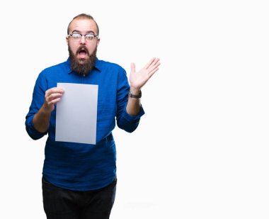 Gözlük takan ve boş kağıt tutan genç hipster adam büyük gülümseme ile çığlık zaferini kutluyor ve ellerini kaldırdı arka plan çok mutlu ve heyecanlı, kazanan ifade izole