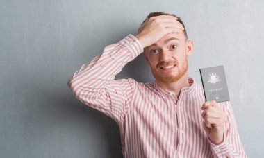 Genç Kızıl saçlı adam kafasına, el ile vurguladı Avustralya pasaportu tutan gri grunge duvarın üzerinden şok utanç ve sürpriz suratla, öfkeli ve sinirli. Korku ve hata için üzgün.