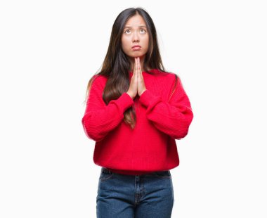 Yalvarıyor ve ellerle birlikte dua izole arka plan üzerinde kış kazak giyen genç Asyalı kadın