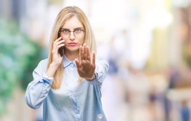 Genç güzel sarışın iş kadını Smartphone'da açık eliyle dur işareti ile ciddi ve kendine güvenen ifade, savunma jest yapıyor izole arka plan üzerinde arama