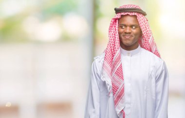 Geleneksel keffiyeh görünümlü yan ve dik dik bakma uzağa düşünce gülümseyen izole arka plan üzerinde giyen genç Arapça Afrika adam.