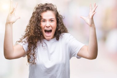 Kızgın ve silah ile başarı için deli izole arka plan kutluyor üzerinde rahat t-shirt giyen genç kız kaldırdı ve heyecanlı çığlık gözleri kapalı güzel esmer kıvırcık saçlı. Kazanan kavramı