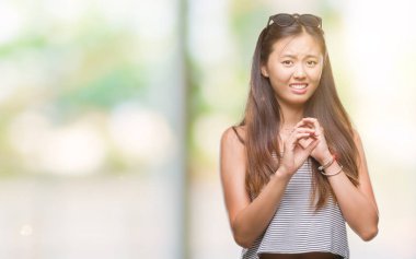 Genç Asyalı kadın izole arka plan üzerinde güneş gözlüğü takıyor ifade tiksinti