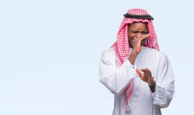 İzole arka plan kokulu üzerinde geleneksel keffiyeh pis ve iğrenç bir şey, dayanılmaz koku, holding nefes parmak ile burun üzerinde giyen genç Arapça Afrika adam. Kötü kokuyor kavramı.