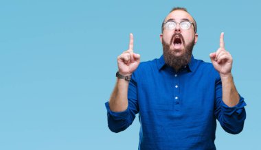 İzole arka plan üzerinde gözlüklü Genç beyaz hipster adam hayret ve yukarıya bakıp parmakları ile işaret şaşırttı ve silah kaldırdı.