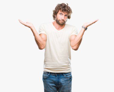 Yakışıklı İspanyol modeli adam izole arka plan clueless ve şaşkın bir ifadeyle kollar ve eller kaldırdı. Şüphe kavramı.