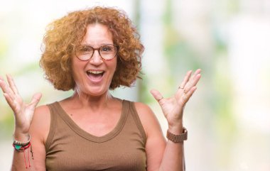 Orta yaş İspanyol kadın üzerinde gözlük takan deli kutluyor arka plan izole ve silah ile başarı için yükseltilmiş ve açık gözleri heyecanlı çığlık hayrete düşürdü. Kazanan kavramı