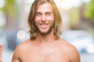 Genç yakışıklı gömleksiz adam uzun saçlı seksi vücut gösterilen ve parmakları ile işaret izole arka plan üzerinde gösterilen üçüncü ise kendinden emin ve mutlu gülümseyerek.