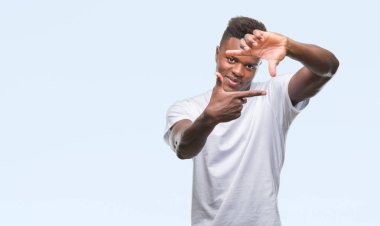 Afrikalı-Amerikalı genç elle yapma çerçeve ve parmakları ile mutlu yüz gülümseyen izole arka plan üzerinde. Yaratıcılık ve Fotoğrafçılık kavramı.