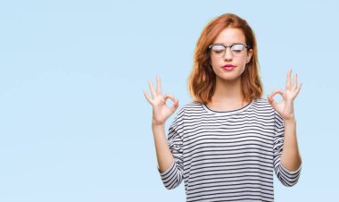 Gözlük rahatla izole arka plan ve gözleri ile gülümseyen genç güzel kadın meditasyon jest parmak ile yapıyor kapalı. Yoga kavramı.