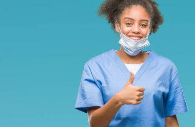 Genç afro Amerikalı doktor kadın hareketi el ile mutlu yaşasın yapıyor izole arka plan yüzünden. Kameraya bakarak başarı gösteren ile ifade onaylama.