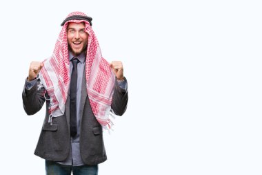 Genç yakışıklı Arap adam uzun saçlı keffiyeh izole arka plan kutlama üzerinde giyen şaşırttı ve başarı için kaldırdı kollarını açarak hayret ve gözleri açık. Kazanan kavramı.