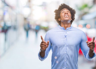 Afro Amerikalı adam izole arka plan üzerinden hayran ve yukarıya bakıp parmakları ile işaret şaşırttı ve silah kaldırdı.