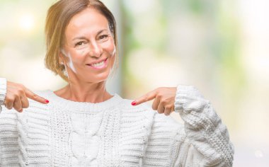 Yüzünde gülümseme ile kendinden emin görünüyorsun, kendini gururlu ve mutlu parmakları ile işaret izole arka plan üzerinde kış kazak giyen orta yaş üst düzey İspanyol kadın.