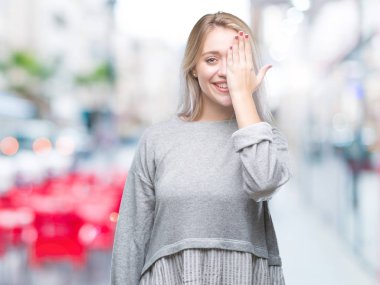 Sarışın genç kadın el yüz ve sürpriz duygu kendinden emin gülümseme ile tek gözüyle kapsayan izole arka plan üzerinde.