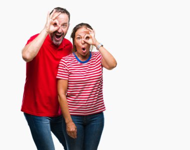 Orta yaş İspanyol çift ok jest sürpriz yüz ile şok yapıyor izole arka plan üzerinde aşık göz parmaklarının arasından arıyorum. İmansız ifade.