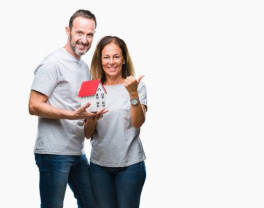 Orta yaş İspanyol rahat çift işaret ve başparmak kadar mutlu yüz gülümseyen tarafı ile gösteren izole arka plan üzerinde yeni bir ev satın alma