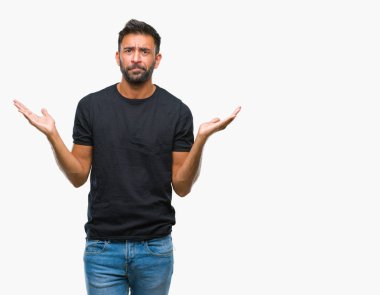 İzole arka plan clueless ve şaşkın bir ifadeyle kollar ve eller kaldırdı yetişkin İspanyol adam. Şüphe kavramı.