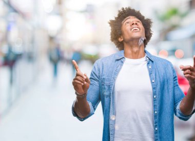 Afro Amerikalı adam izole arka plan üzerinden hayran ve yukarıya bakıp parmakları ile işaret şaşırttı ve silah kaldırdı.