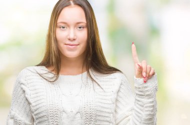 Ve parmak gülümseyen süre bir numara ile kendinden emin ve mutlu yukarıyı gösteren izole arka plan üzerinde kış kazak giyen genç güzel beyaz kadın.