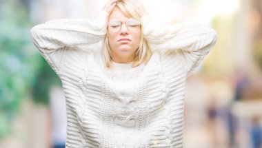 Kış kazak ve gözlük çünkü umutsuz ve stresli baş ağrısı acı izole arka plan üzerinde giyen genç güzel sarışın kadın ağrı ve migren. Ellerini kafasına.