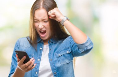 Genç güzel beyaz kadın manifatura öfke, çılgın ve yükseltilmiş el, öfke kavramı ile diye bağıran ile smartphone üzerinde izole arka rahatsız ve sinirli bağırarak kullanarak ileti gönderme